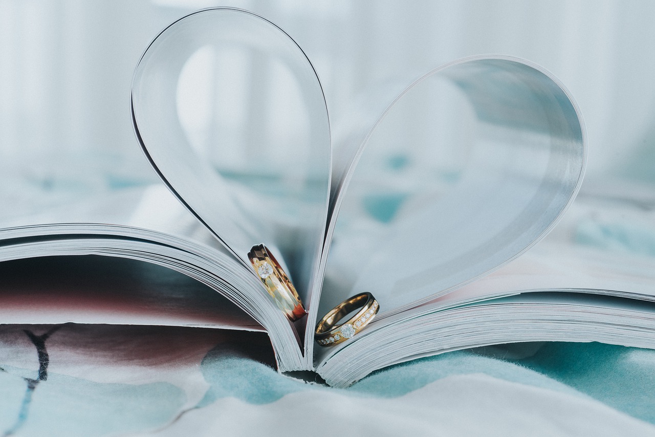 Ringe Zwei Eheringe in einem Buch, das zu einem Herz geformt ist