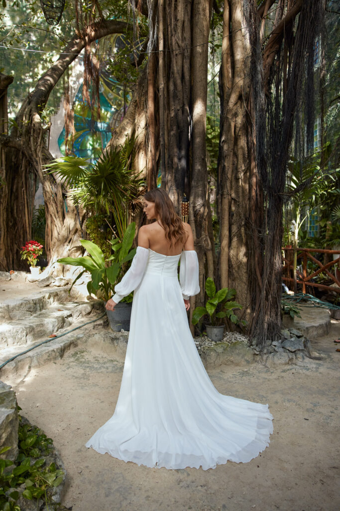 Libelle Esperienza Hochzeitskleid Hollis von hinten im Wald zwischen Bäumen