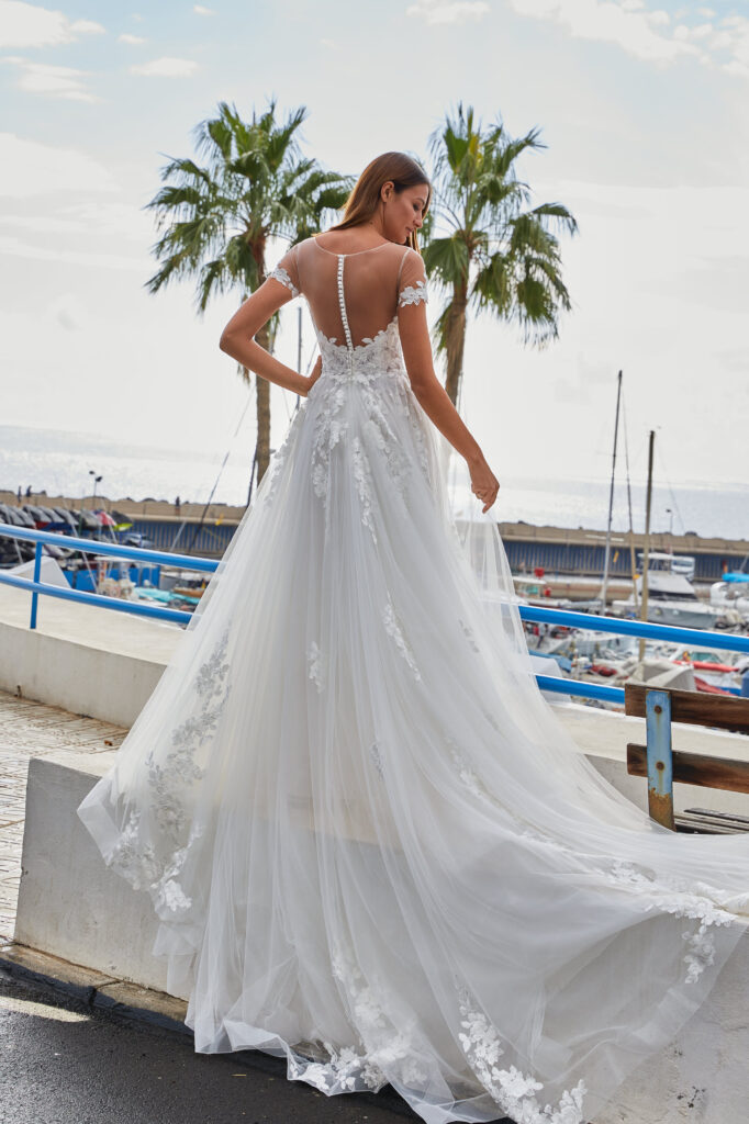 Frau steht am Hafen am Meer im Hochzeitskleid Dreamy von Euro Mode.