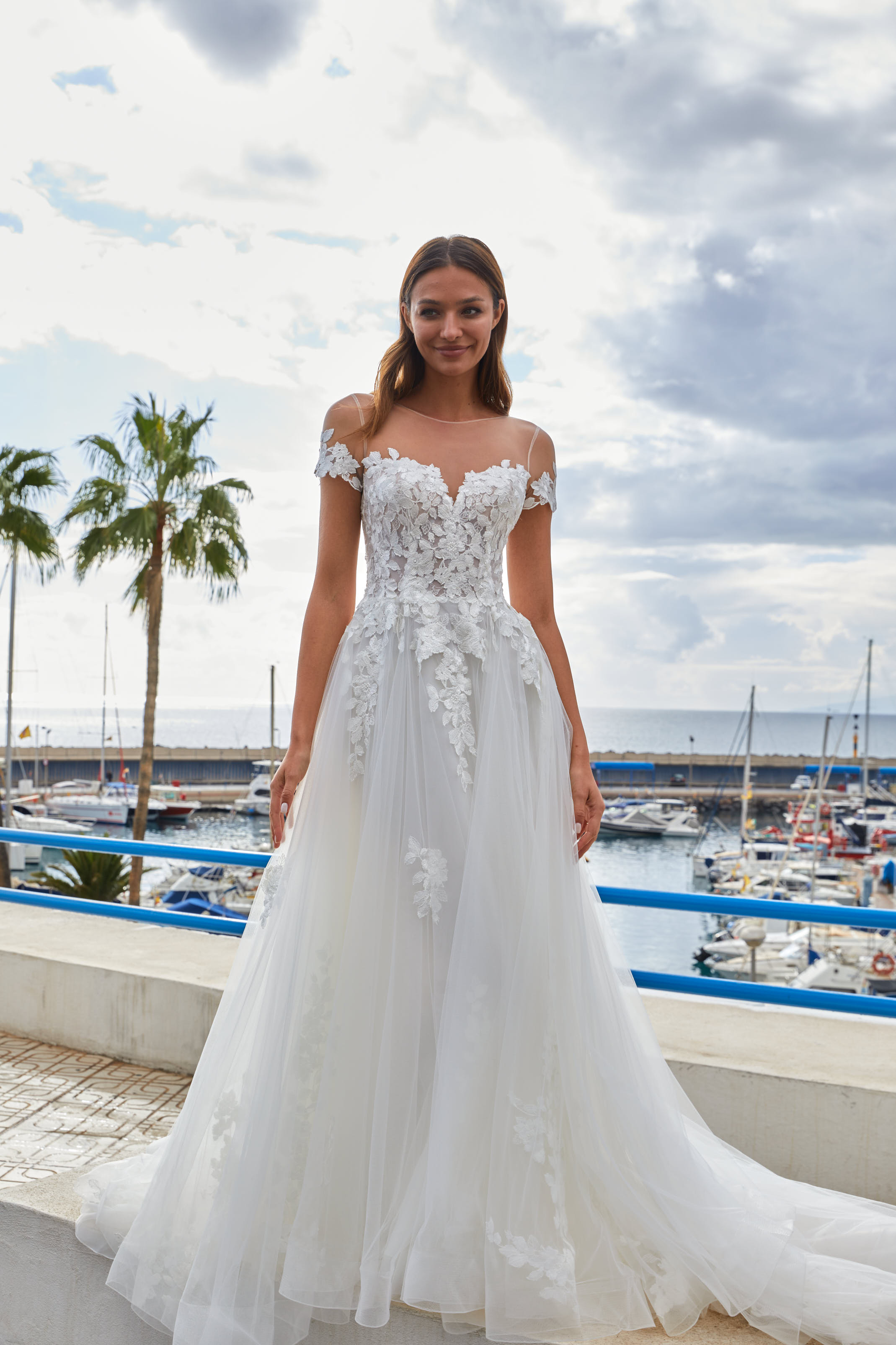 Braut in Dreamy Brautkleid von Euro Mode vor einem kleinen Hafen am Meer.