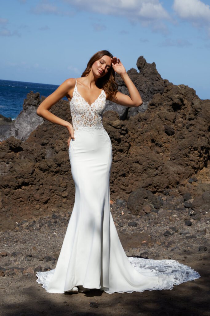 Braut steht am Meer vor den Klippen und trägt ein Hochzeitskleid von Euro Mode aus der Diane Legrand Kollektion.